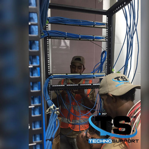 Técnicos organizando el cableado de red en un rack
