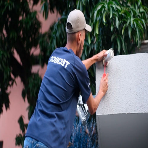 Técnico instalando una cámara de seguridad en una pared exterior